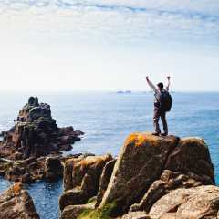 Hiker with arms up in front of the sea in UK